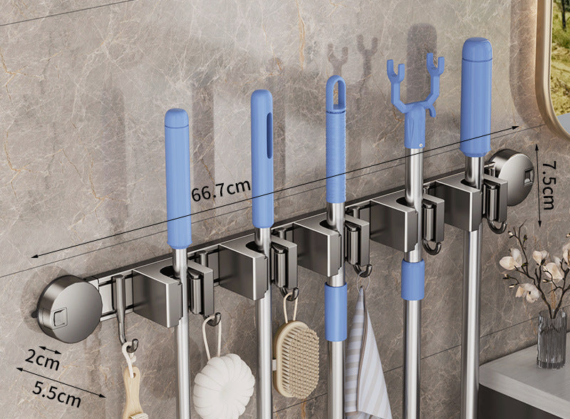 Wall-mounted cleaning tool holder with brooms and mops on a tiled wall background