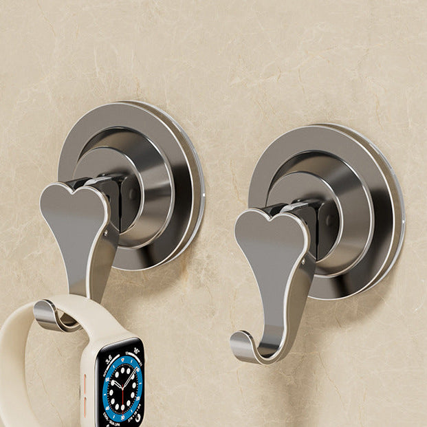 Two metal wall hooks with a watch on a beige wall background