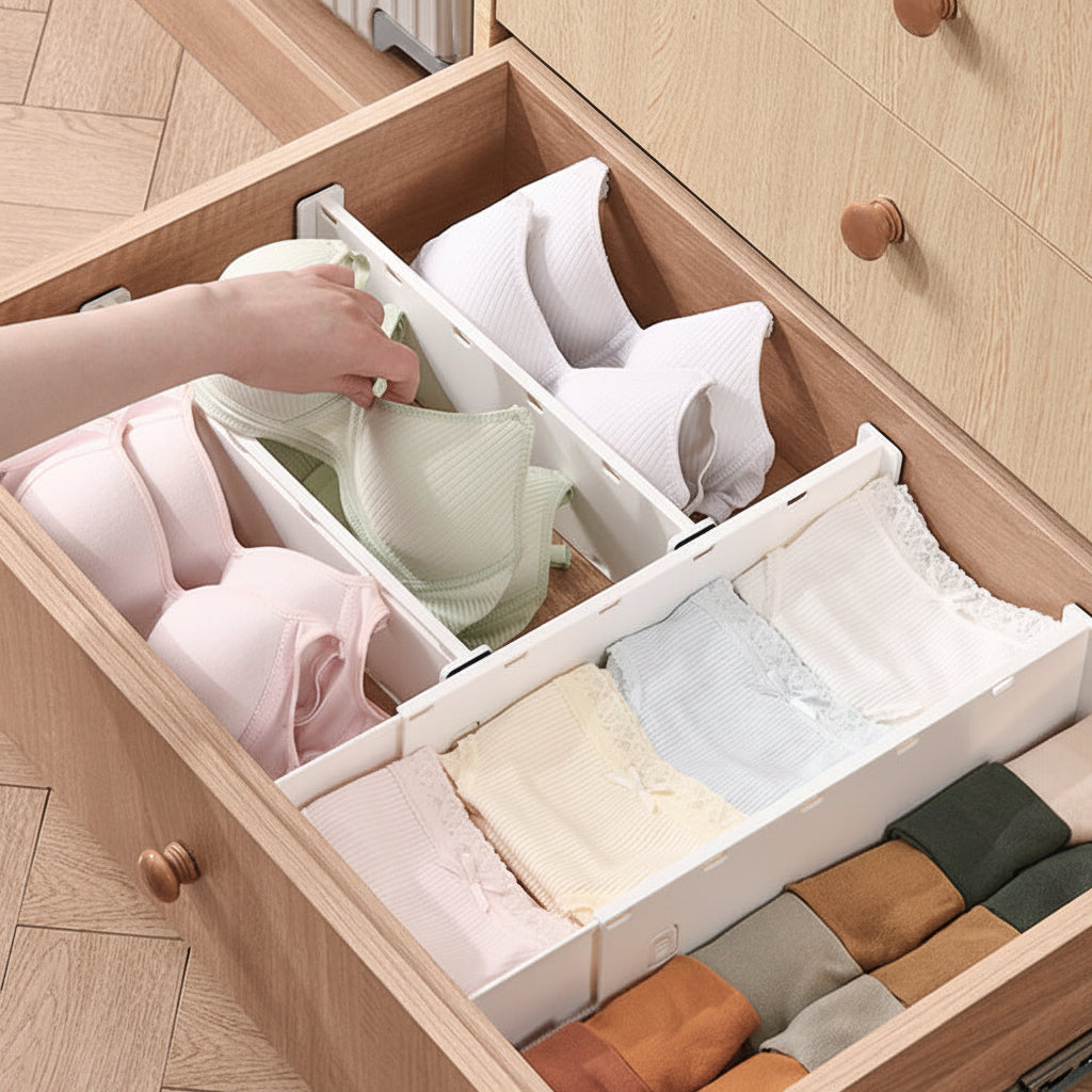 Wooden drawer with organizer holding folded clothes, hand reaching in to adjust items.