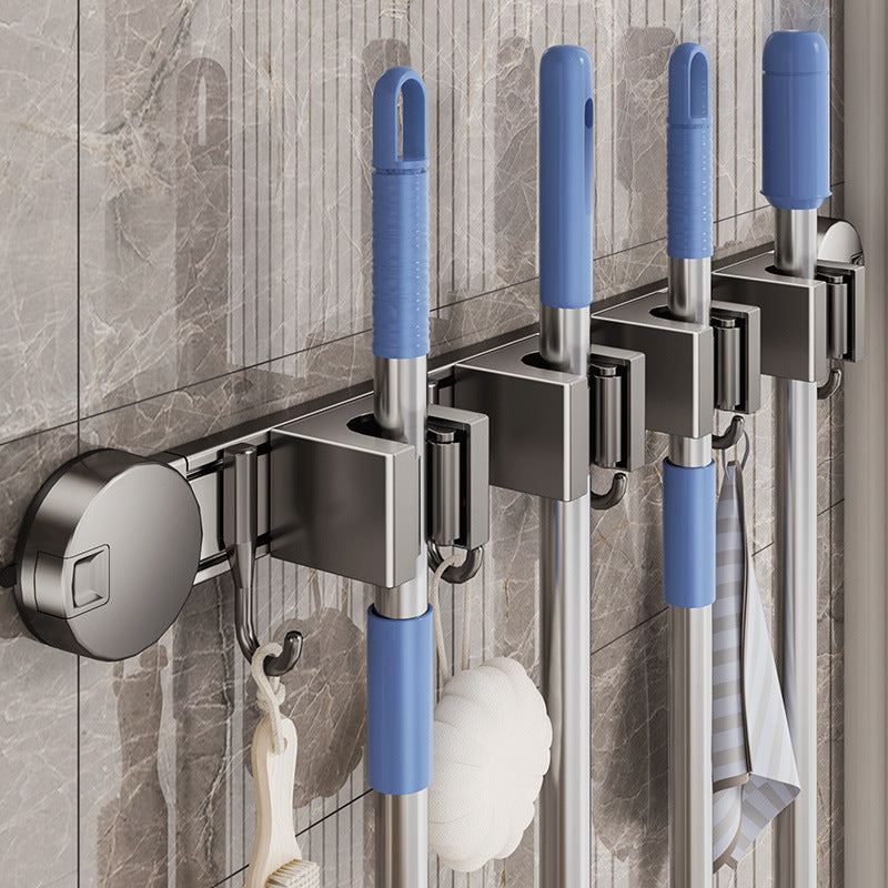 Wall-mounted cleaning tool holder with blue-handled brushes on a tiled wall.